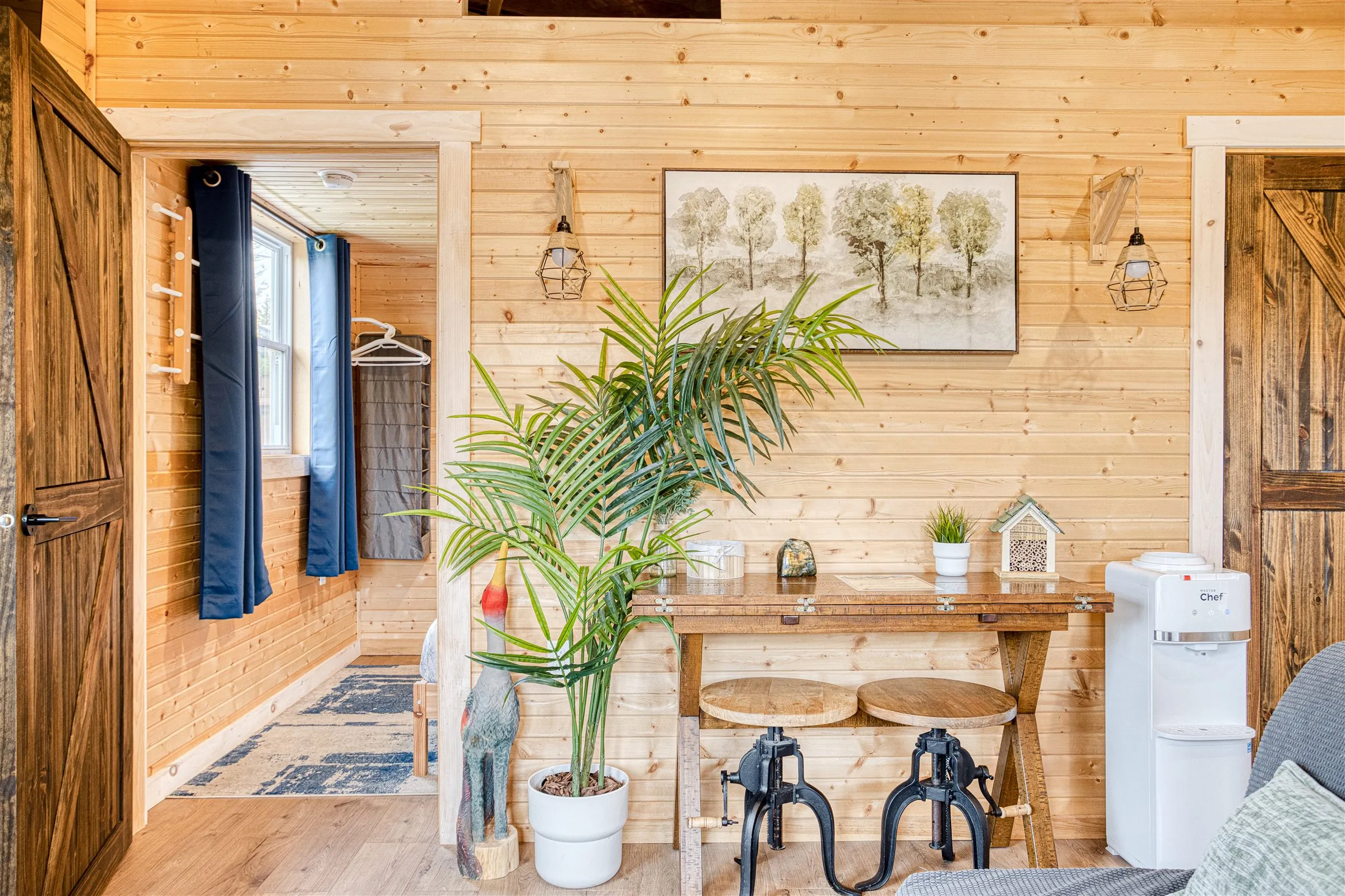 Entry console with stools and a palm beside barn doors leading into the bedroom.
