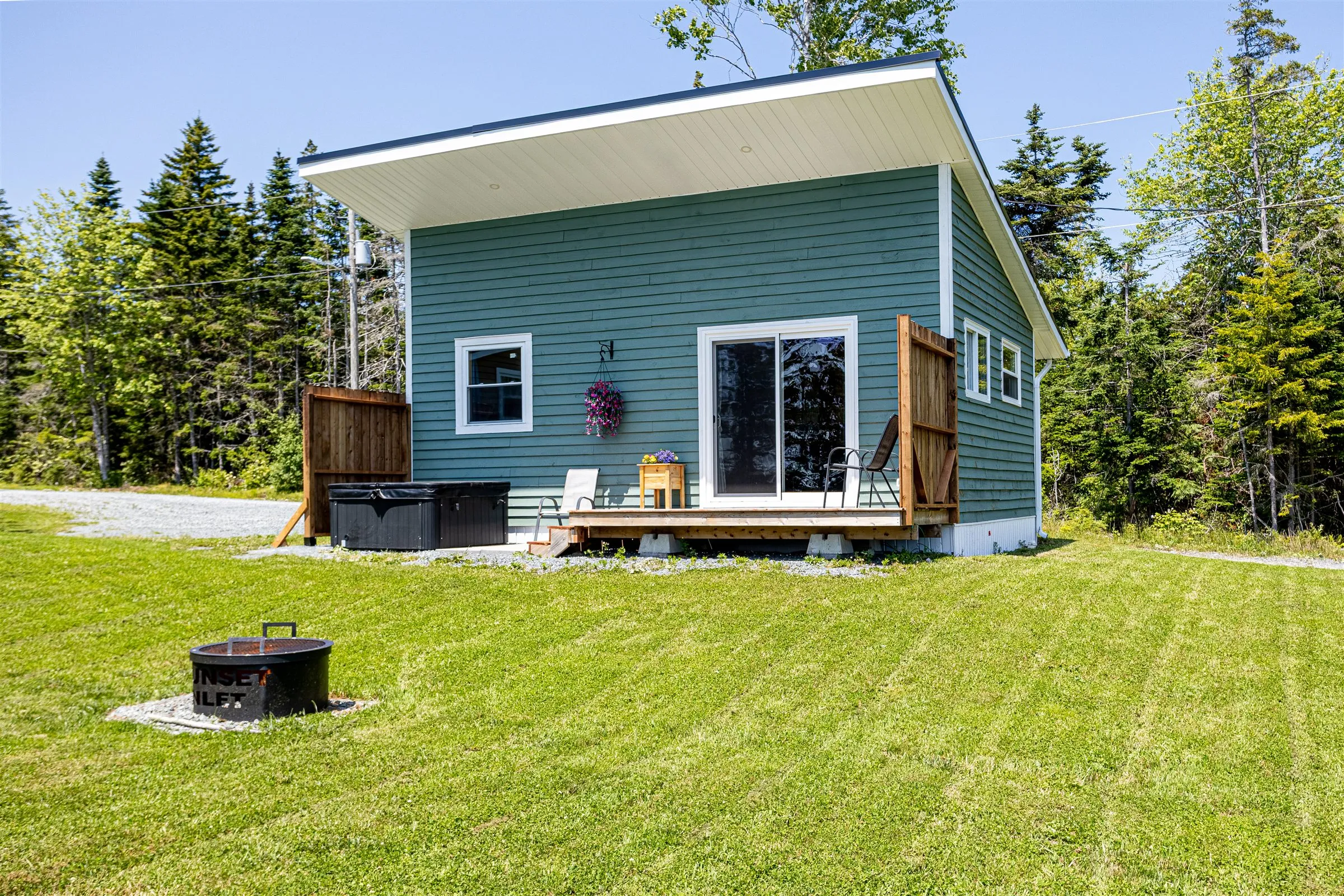 Angled view of the cabin showing its deck, cedar privacy fence, and fire pit in the grass.