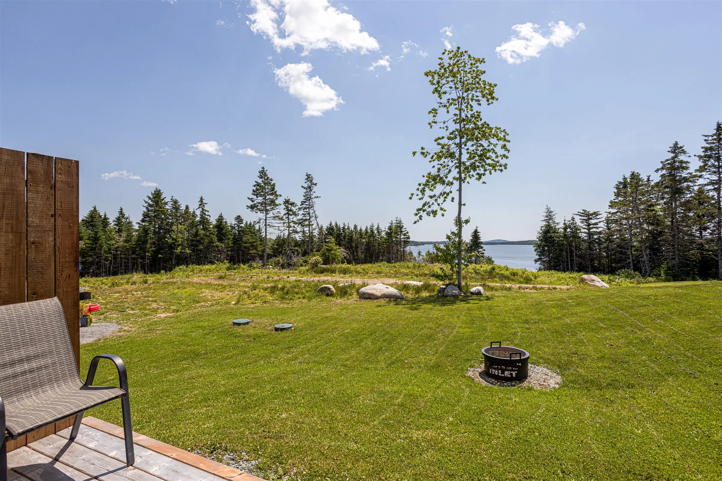 The lawn and fire pit sloping down toward a view of Chezzetcook Inlet.