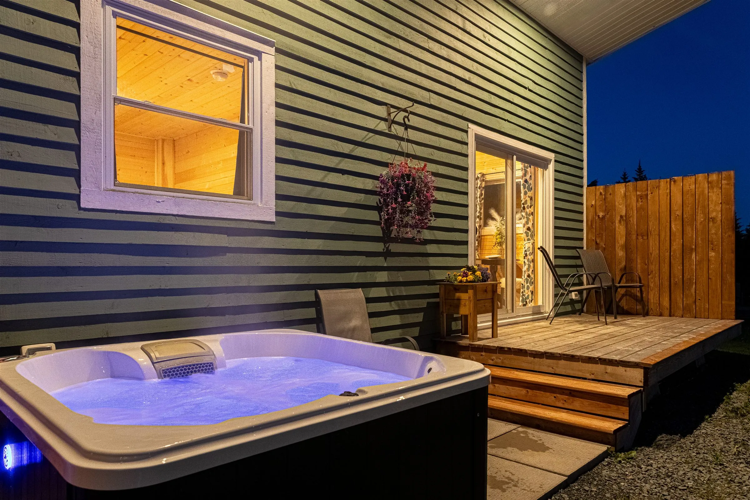 The private hot tub bubbling under an evening sky beside the deck and privacy fence.