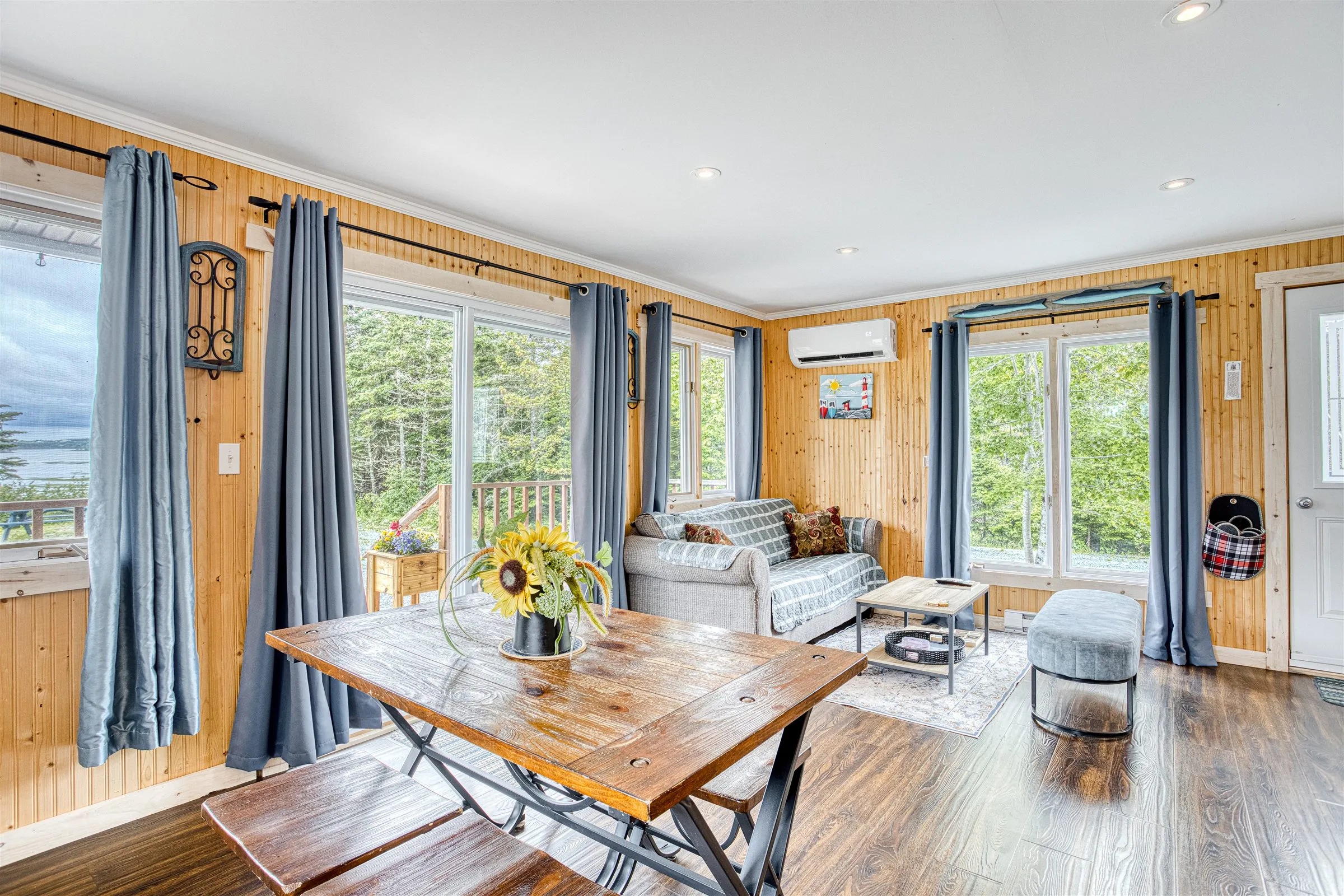Bright living and dining space with wraparound windows and a farmhouse table.