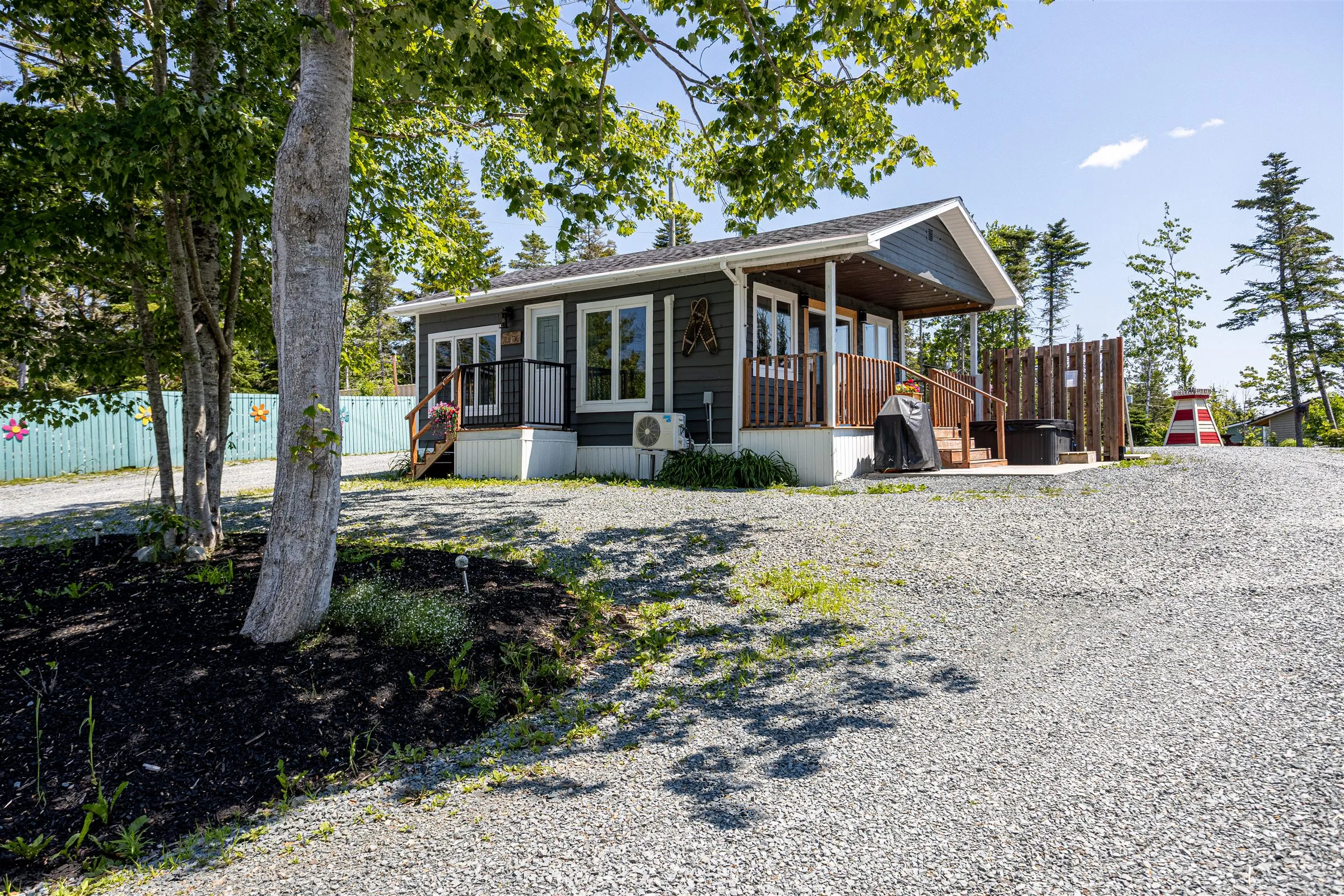 Jolly Tom's Cabin with its deck, privacy-screened hot tub, and lighthouse garden ornament.
