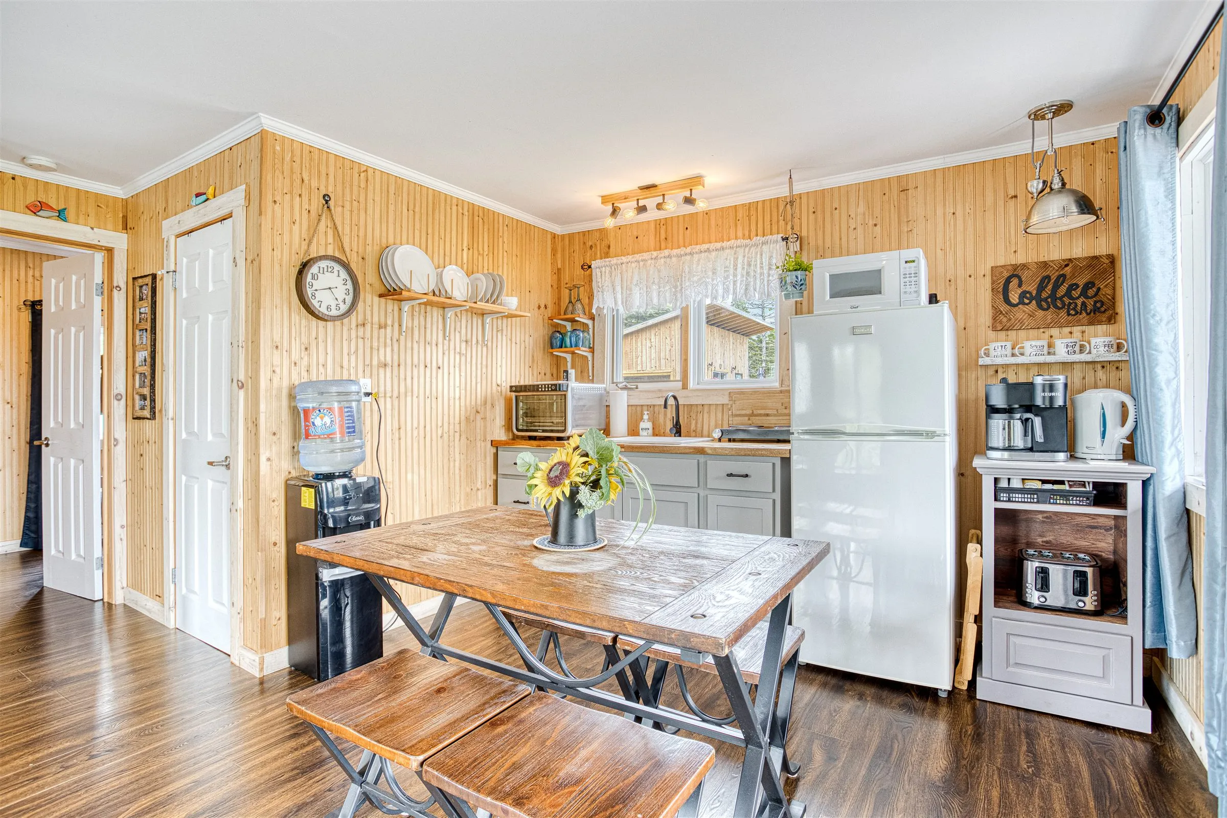 Cabin kitchen with farmhouse dining table, full fridge, and a stocked coffee bar.