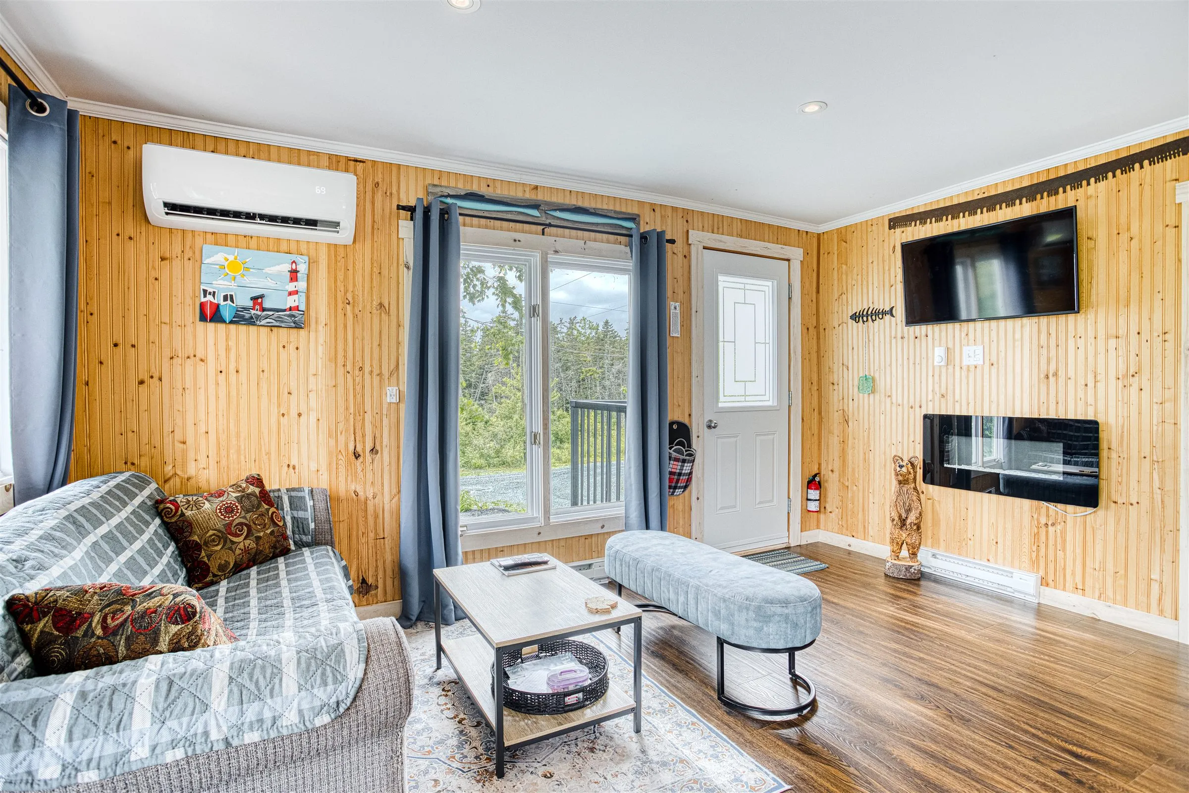 Cabin living room with wall-mounted TV and electric fireplace.