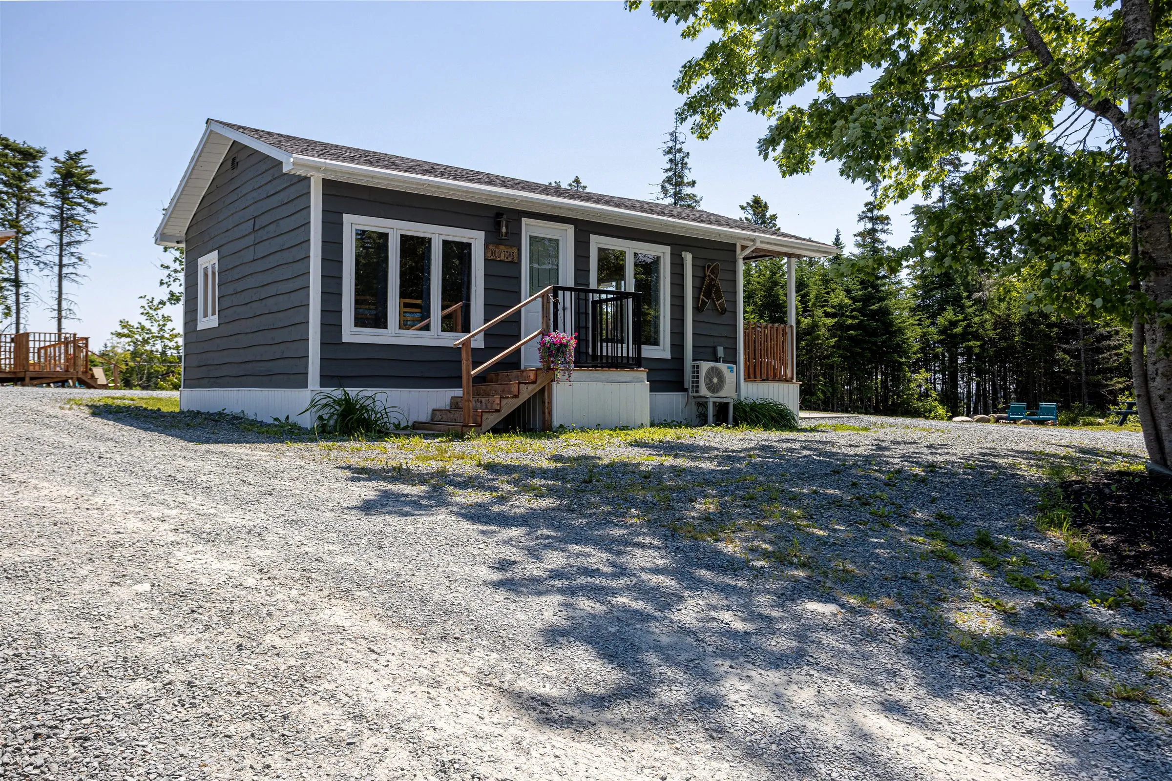 Side view of the cabin with steps up to its covered porch on a sunny day.