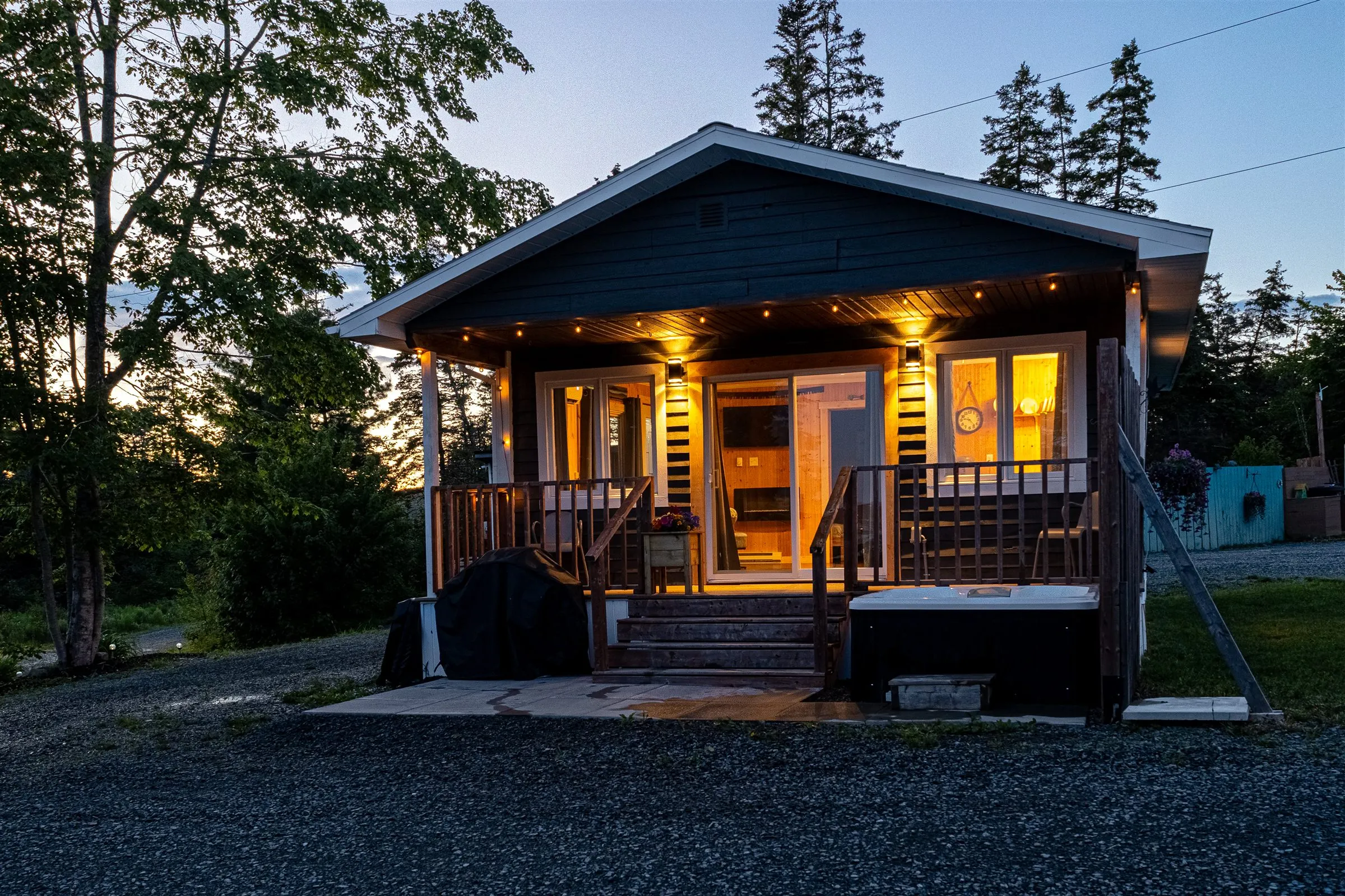Jolly Tom's Cabin at dusk, porch string lights glowing and the last of the sunset behind the trees.