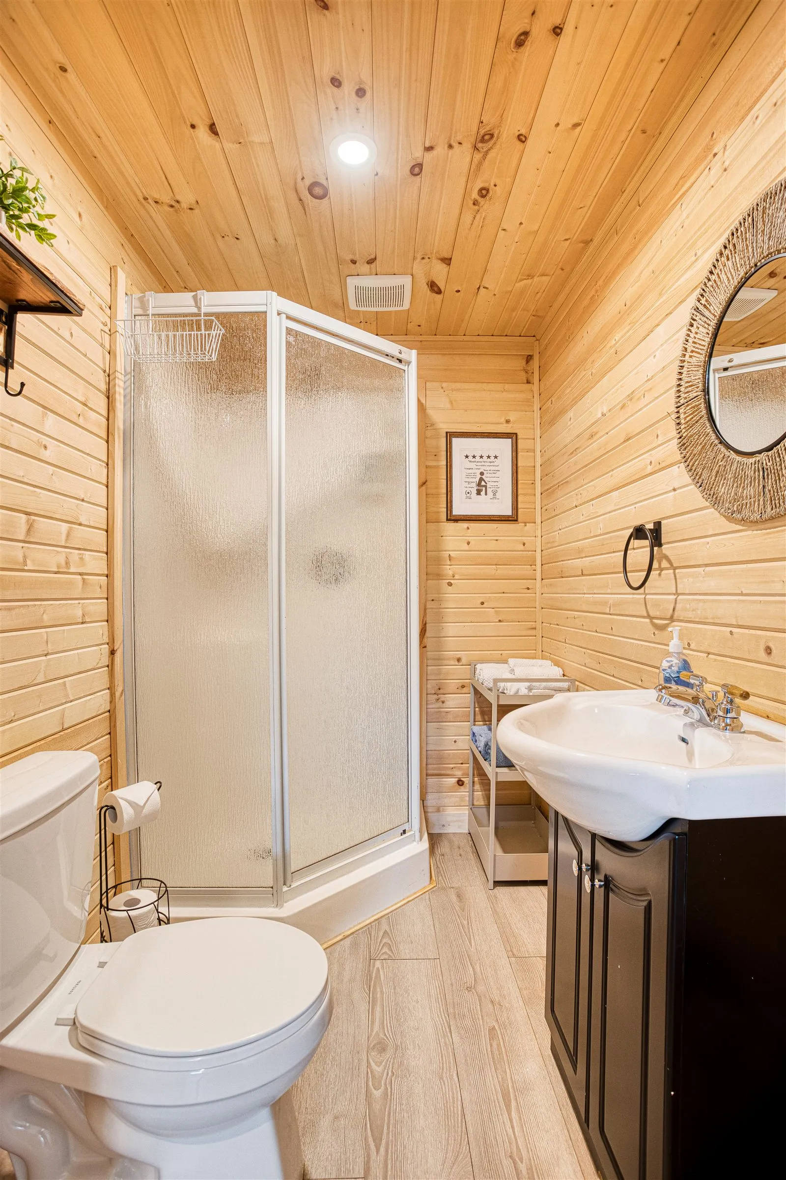 Bathroom with corner shower, dark wood vanity, and warm pine plank walls.