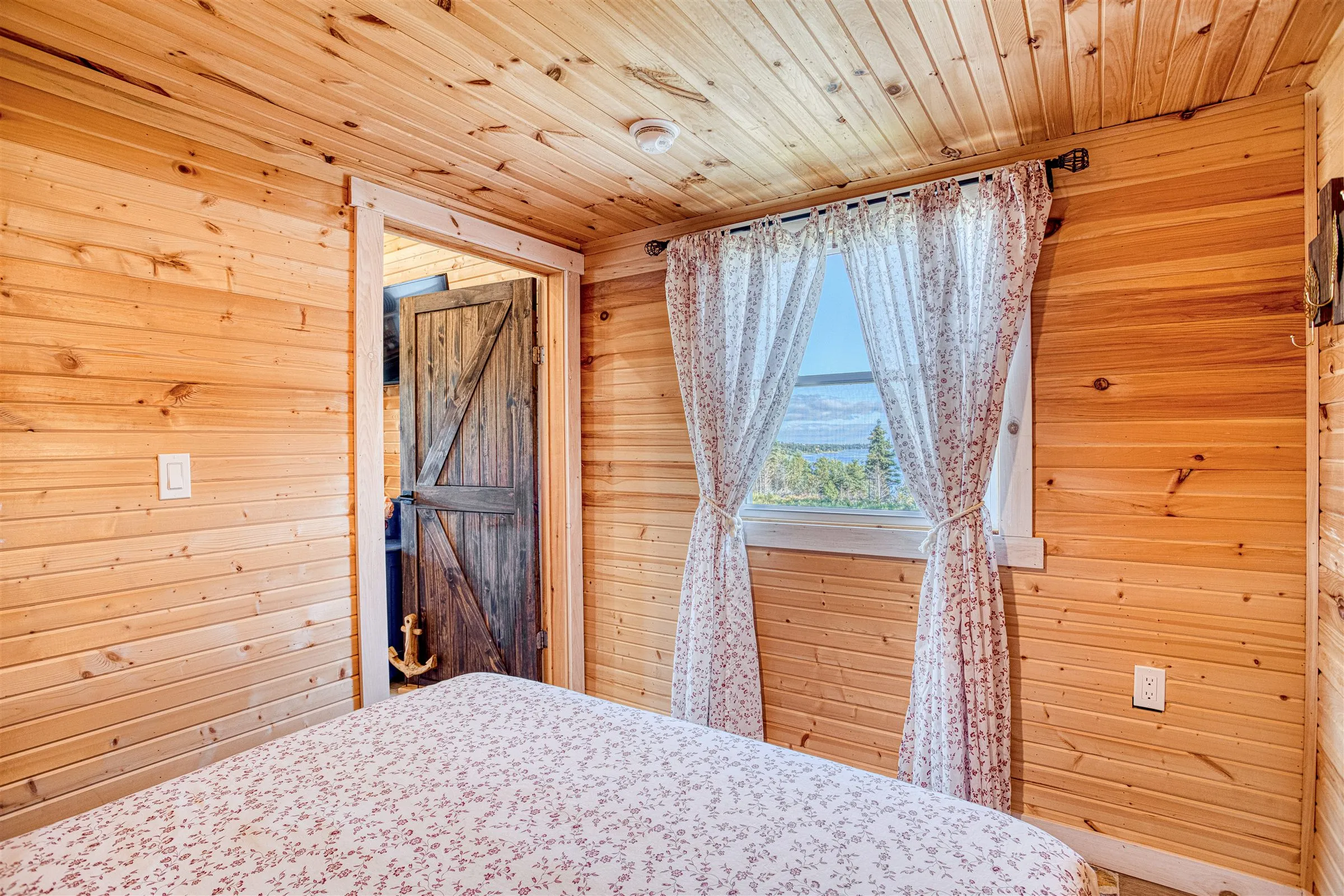Bedroom window looking out over Chezzetcook Inlet, beside a rustic barn-style door.
