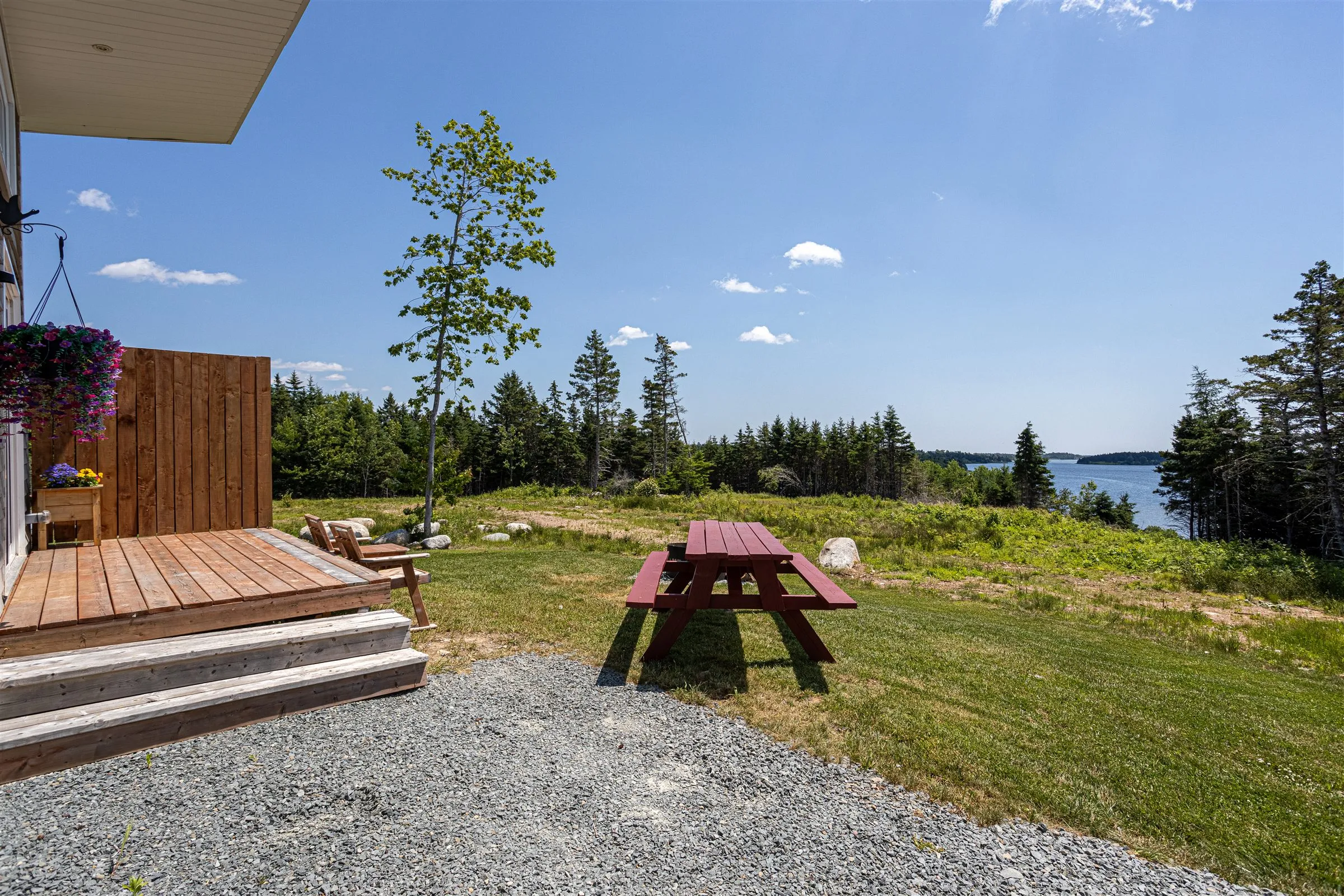 Red picnic table on the lawn beside the deck, looking out over Chezzetcook Inlet.