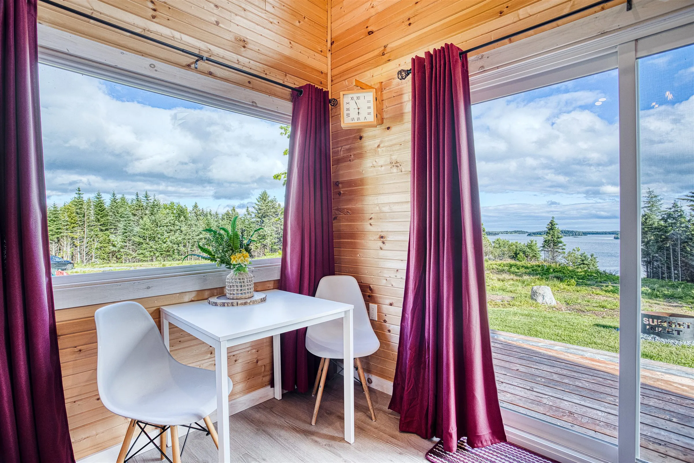 White dining table for two in a corner nook with tall windows overlooking the inlet.