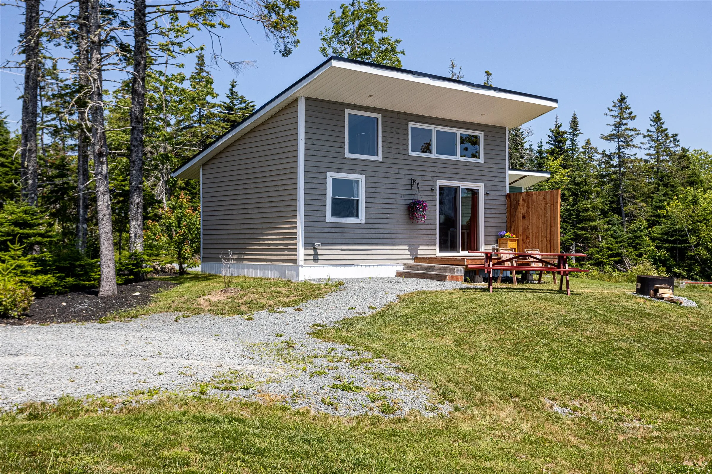 The water side of the cabin with clerestory windows, sliding door, and a red picnic table.