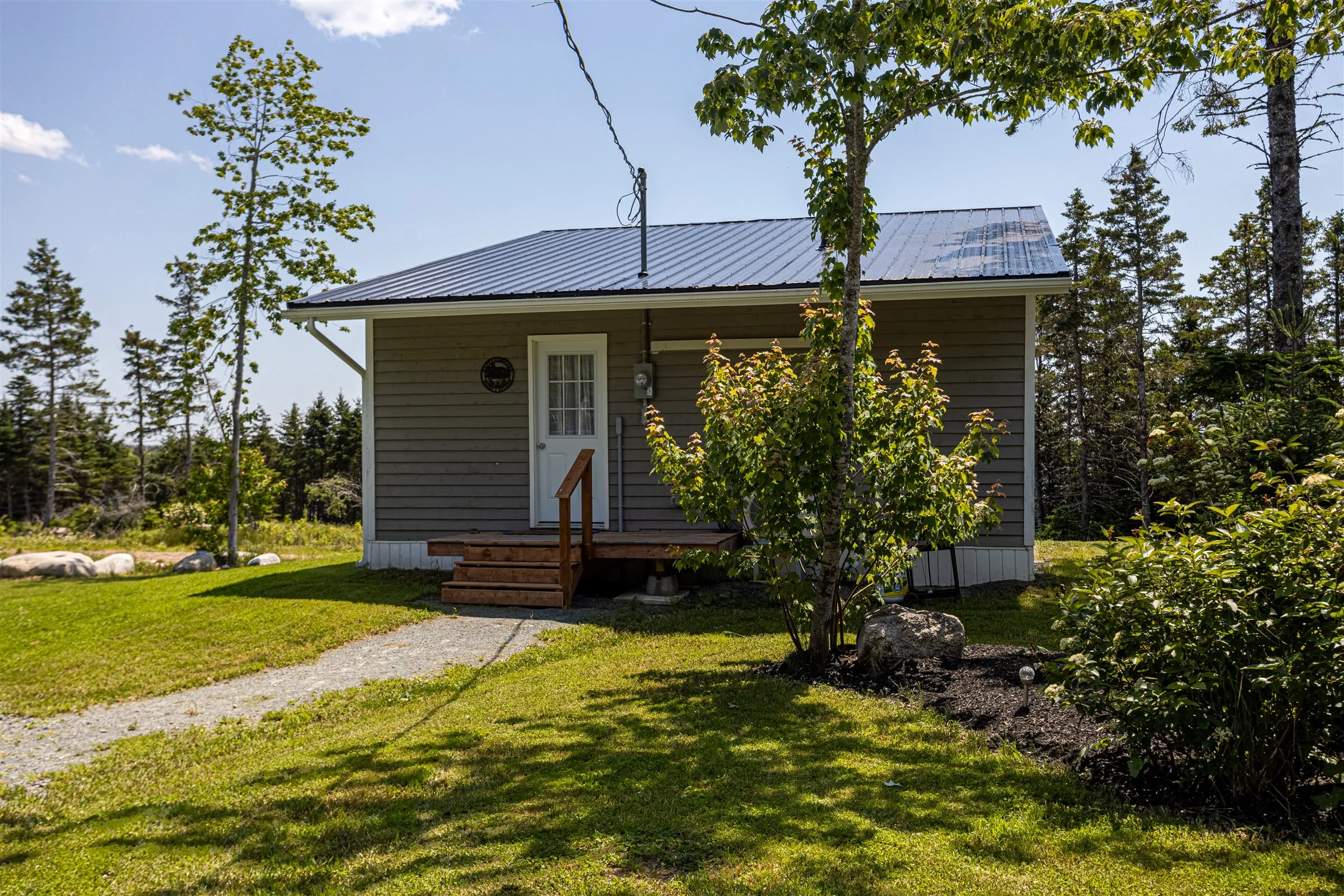 The front of Norma's Retreat: a peaked metal roof, white door, and wooden steps.