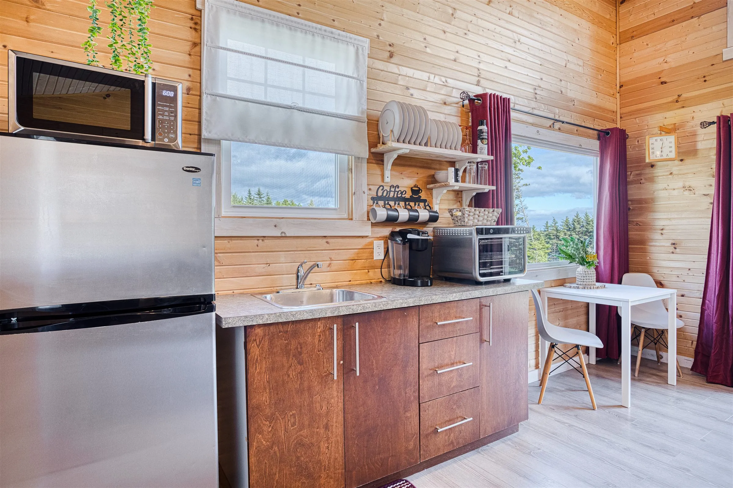 Compact kitchenette with full fridge, coffee maker, and a window over the sink.