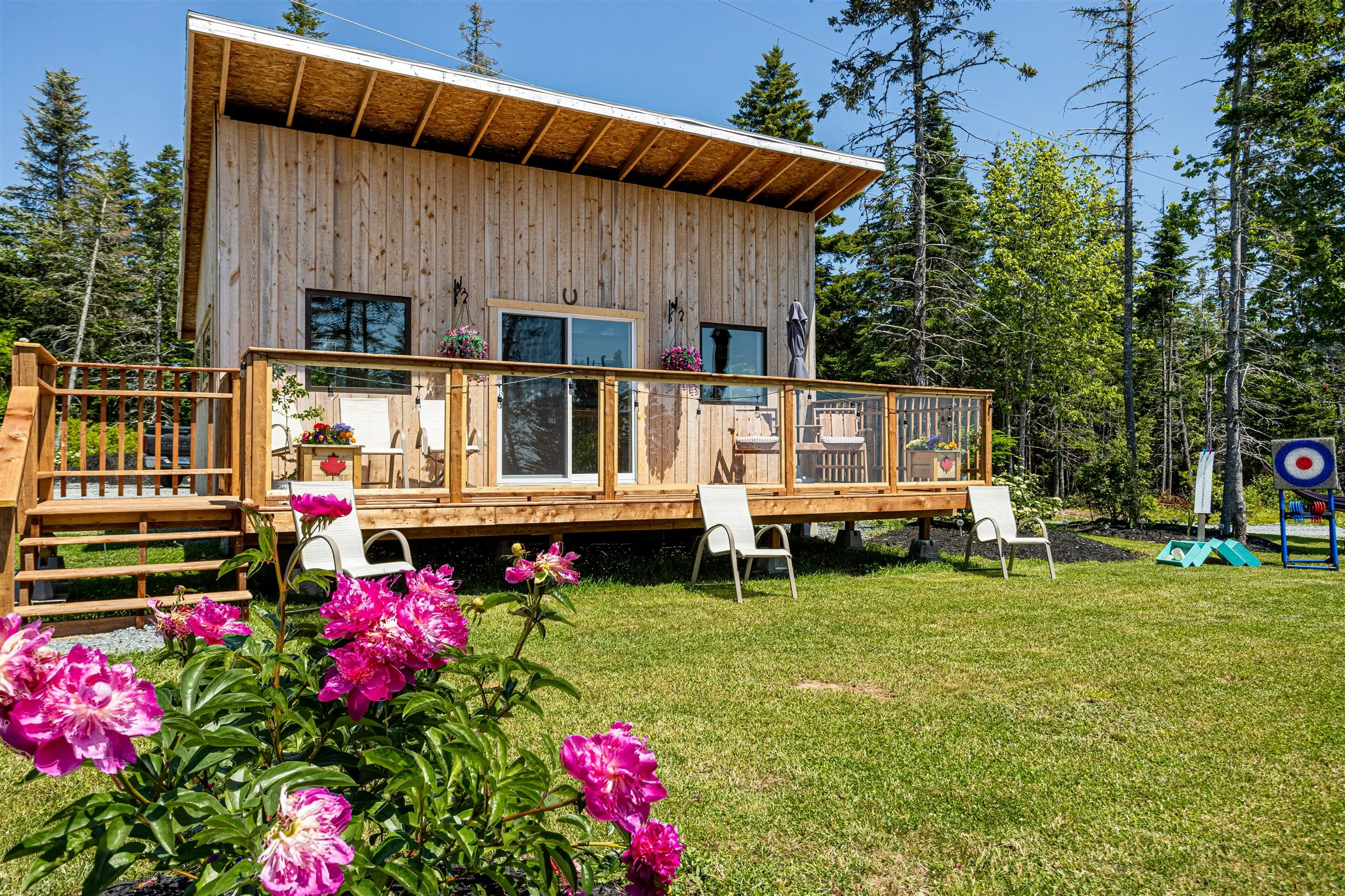 Pink peonies bloom in front of the clubhouse deck and hanging flower baskets.