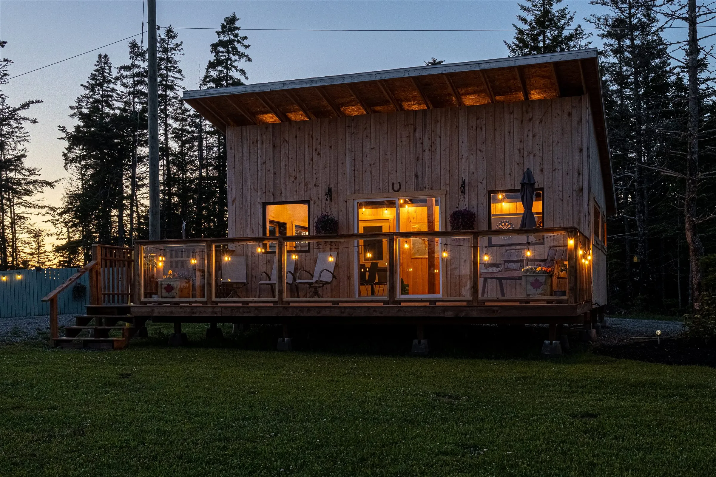 The clubhouse's long patio deck strung with lights, glowing warmly at twilight.