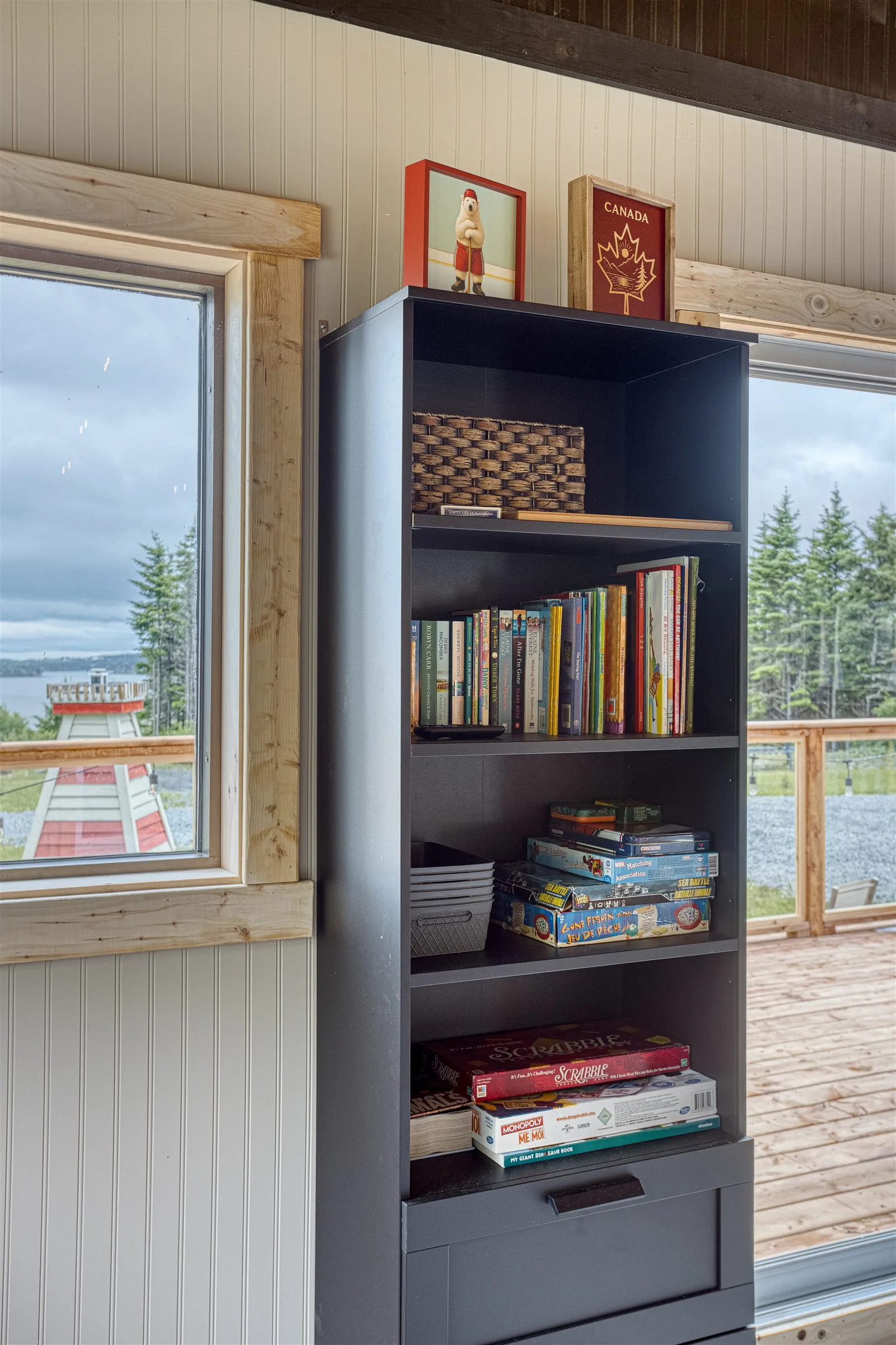 Shelf of board games and books, with Chezzetcook Inlet visible through the window.