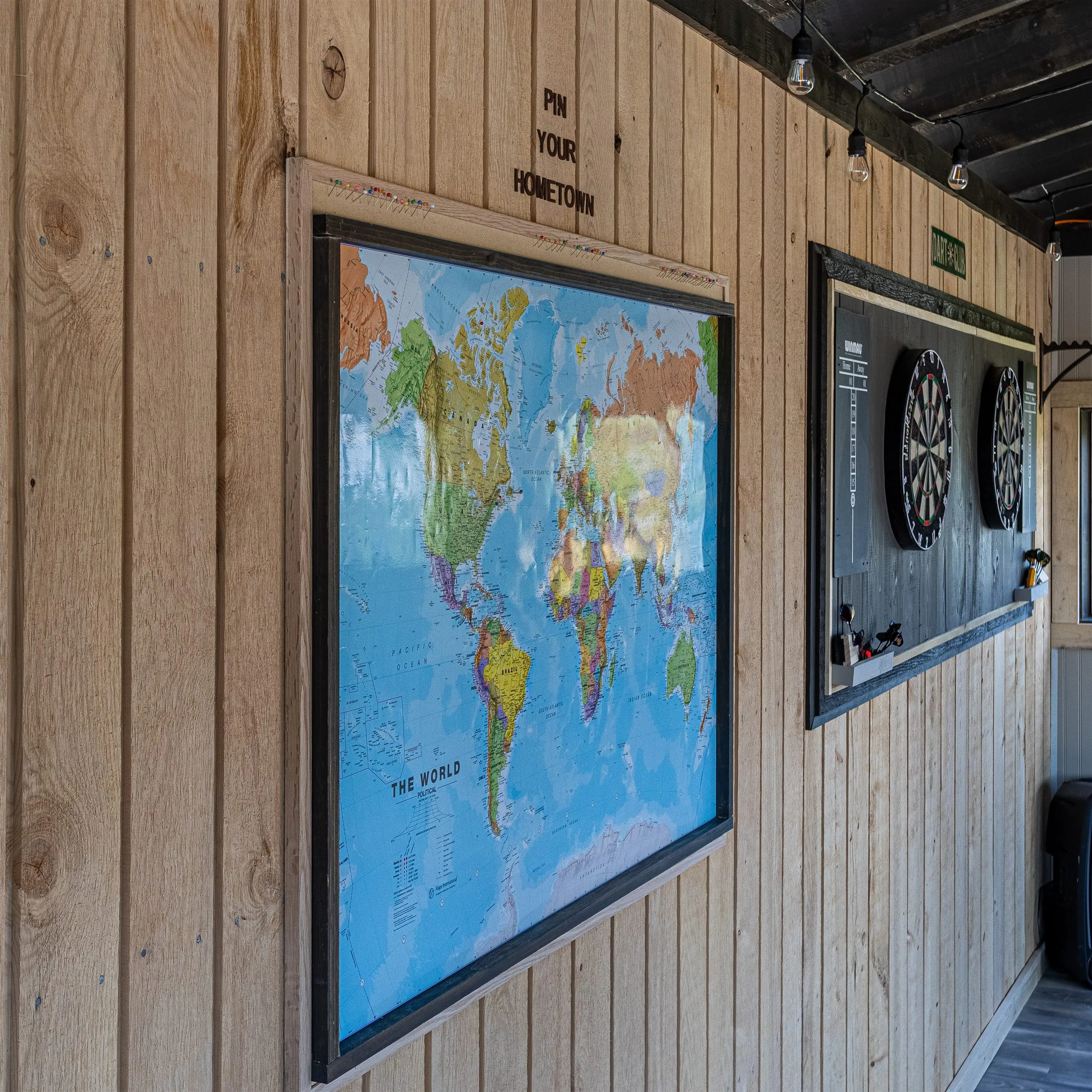 World map where guests pin their hometown, mounted near the dartboards.