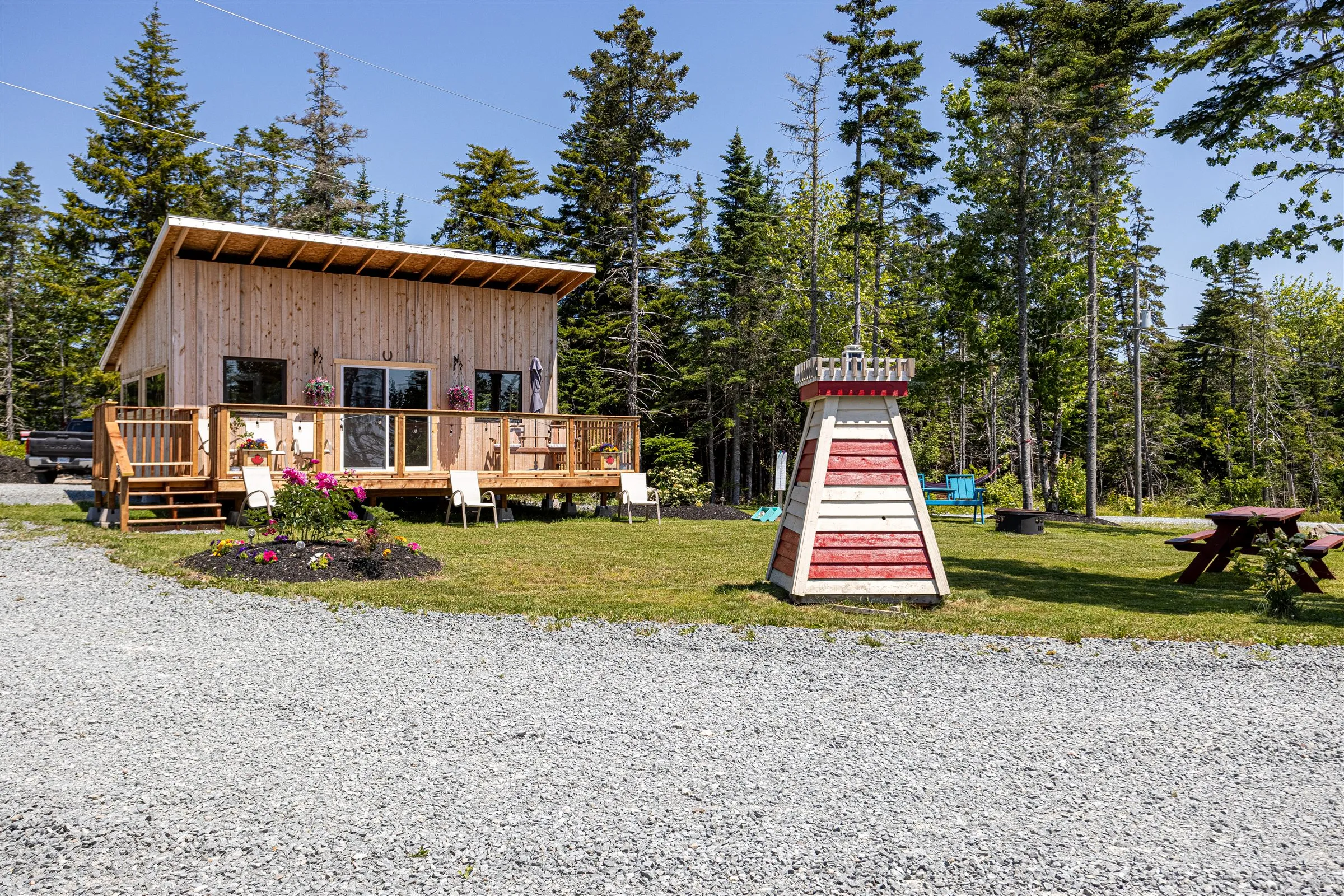 Front lawn of the clubhouse with its wraparound deck, flowerbed, and decorative lighthouse.