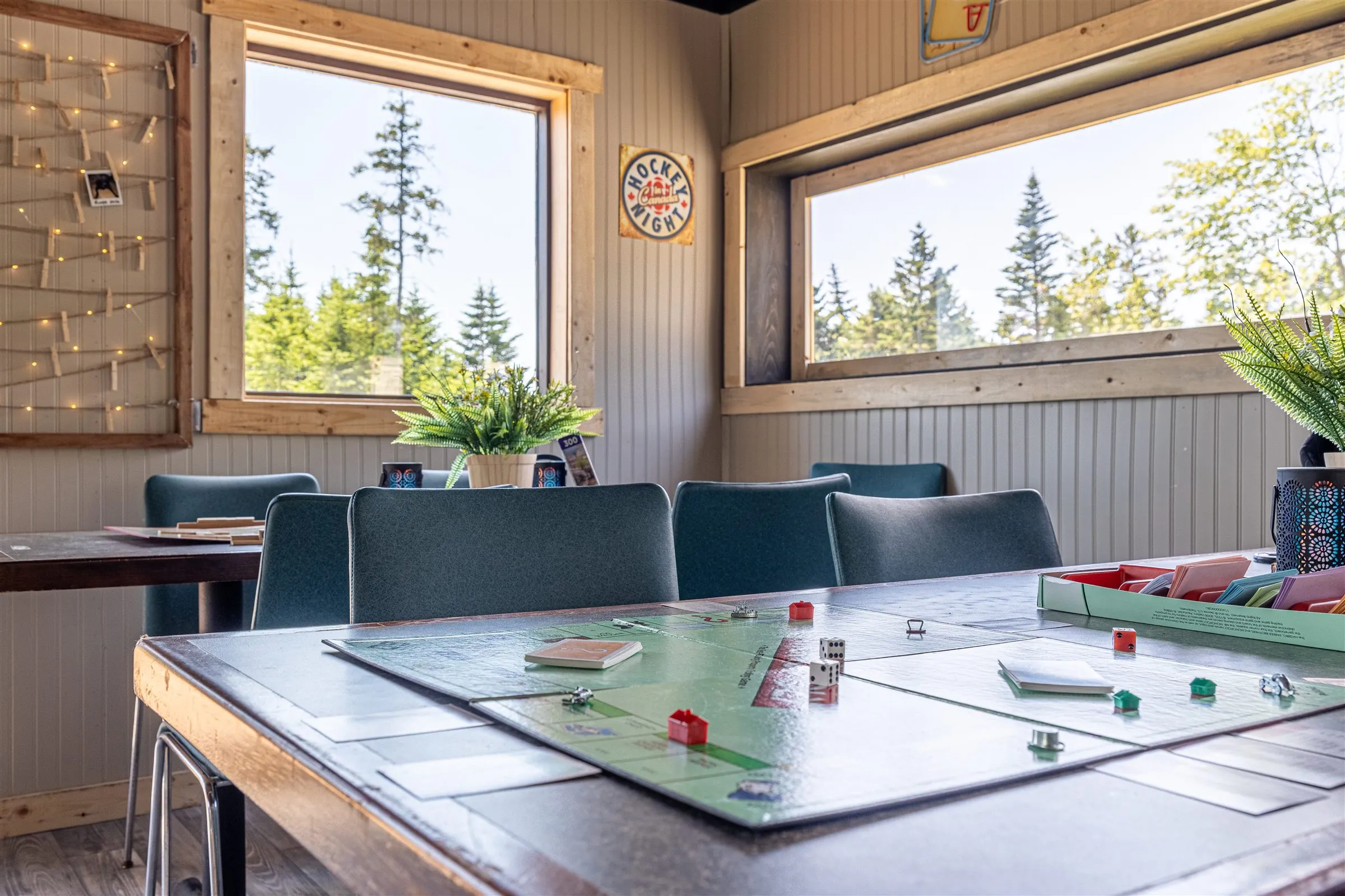 Long shared tables set with board games inside the bright clubhouse.